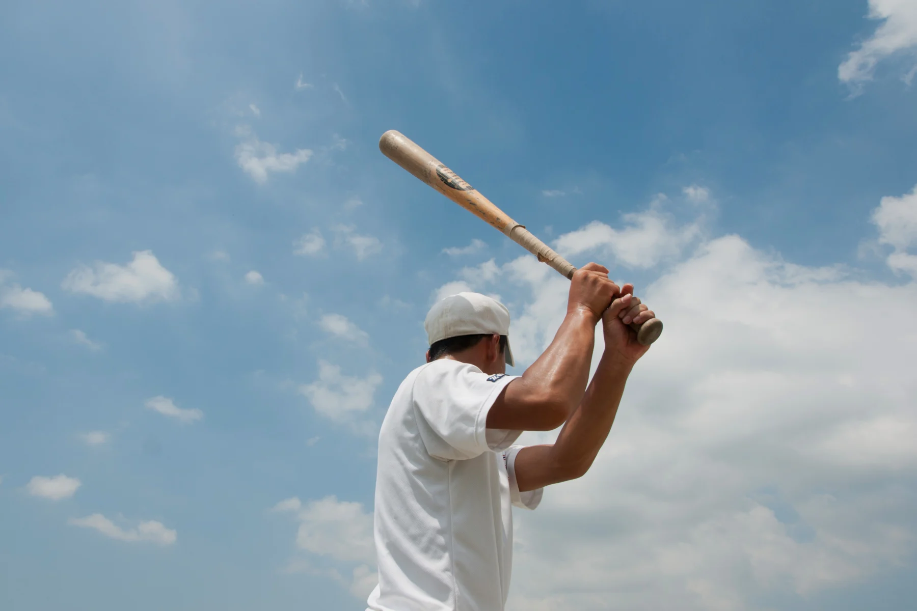 屋外の野球場でスイングフォームを確認しながら素振り練習を行う野球選手