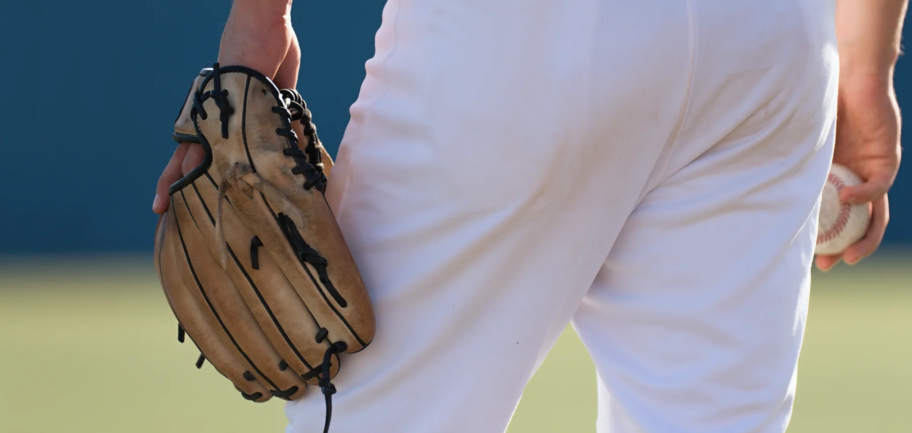スタジアムの照明に照らされる中、グラウンドを見つめて立つプロ野球選手の背中