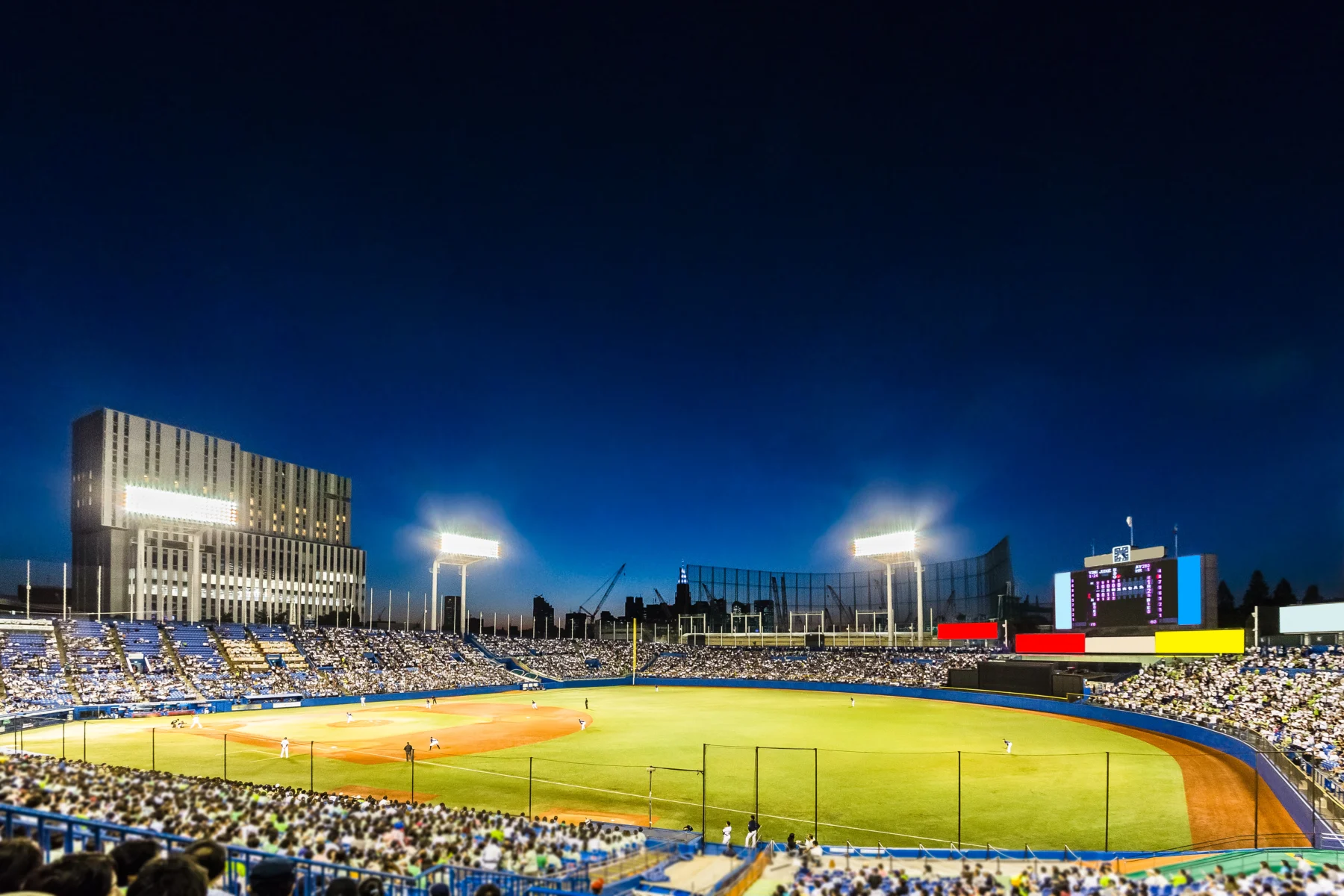 満員の観客が見守る中で試合が行われている緑豊かなプロ野球のスタジアム風景
