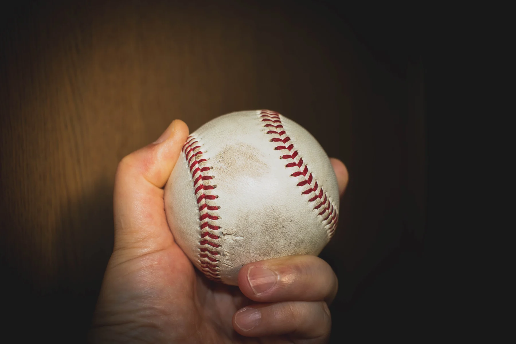 硬式野球ボールを繊細に握り、狙ったコースへ投げ込もうとする投手の手元のアップ