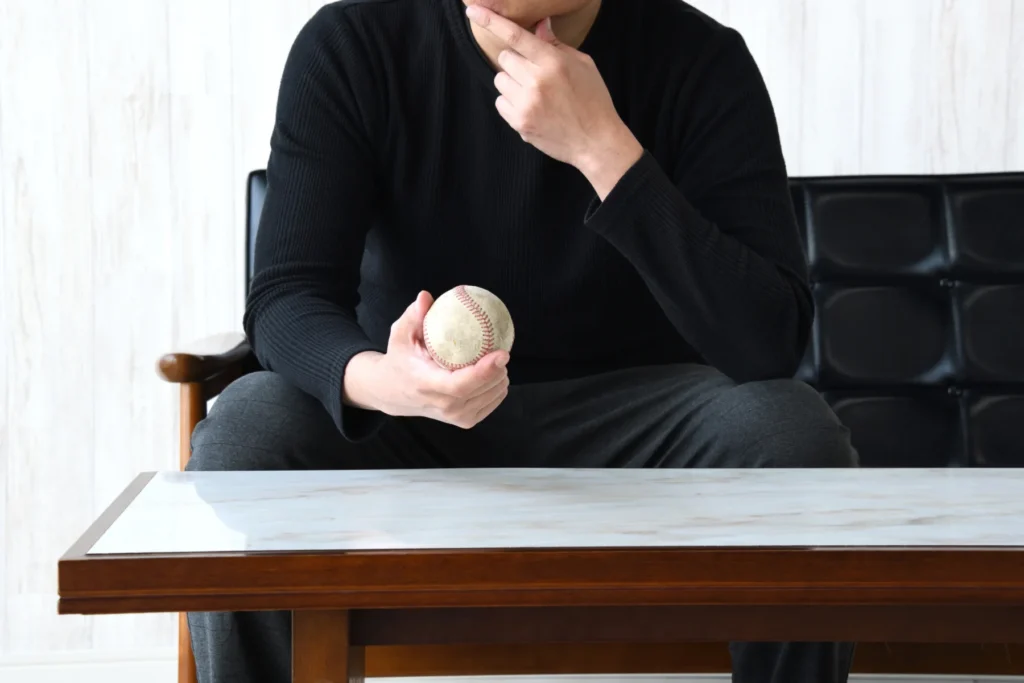 ナイター照明が照らす静かなスタジアムで、グラウンドを見つめるユニフォーム姿の野球選手の後ろ姿