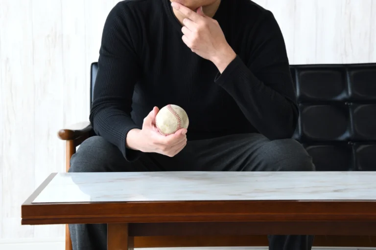 ナイター照明が照らす静かなスタジアムで、グラウンドを見つめるユニフォーム姿の野球選手の後ろ姿
